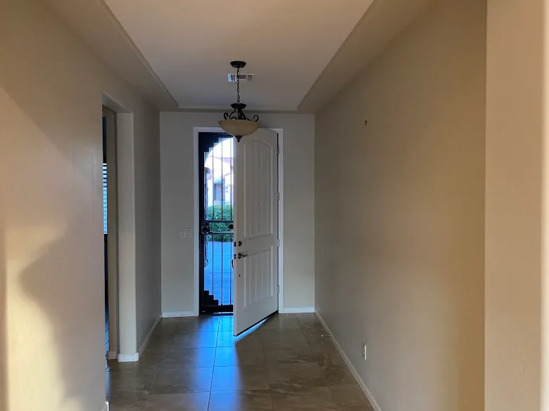 Painted entry hallway with tile floors and front door in an Arizona home